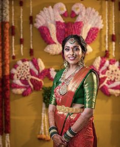 a woman in a red and green sari standing next to flowers on display at a wedding