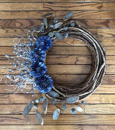 a wreath with blue flowers and leaves on a wooden floor