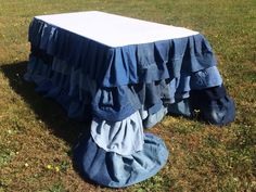 a blue table cloth with ruffles on it sitting in the middle of a field