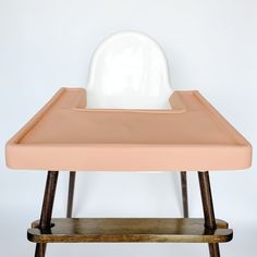 a baby's highchair with a white seat on it and wooden legs