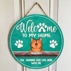 a welcome sign hanging on the front door to someone's home with their cat