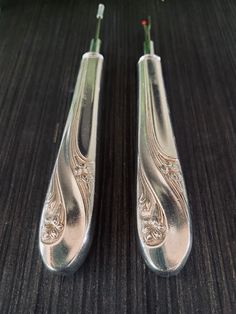 two silver toothbrushes sitting next to each other on a wooden table with flowers in the background