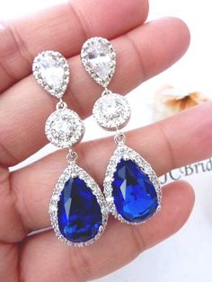 a pair of blue and white earrings on someone's hand, with the top one being