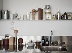 the kitchen sink is full of dishes and utensils on shelves above it,