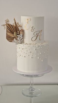 a white wedding cake with gold lettering and flowers