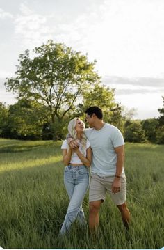 a man and woman standing in tall grass