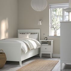 a white bed sitting in a bedroom next to a window