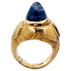 Cabochon Sapphire Ring A unusually tall pyramidical cabochon sapphire ring set in a engraved gold dome band. Accompanied by AGL laboratory certificate stating the sapphire is of Ceylon origin and natural with no treatment Approximate Sapphire Weight: 8 carats Ring Size: 3 Metal Type: 18k yellow gold Vintage Sapphire Ring, Sapphire Cocktail Ring, Saphir Ring, Vintage Sapphire, Vintage Style Rings, Diamond Cocktail Rings, Gold Ring Sets, Cabochon Ring, Sapphire Diamond Ring