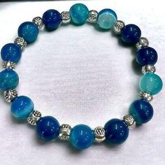 This bracelet features 10mm Natural Blue Striped Agate Stone Beads, with 8mm silver color rondelle spacer beads made with super strong stretchy elastic so it can be worn all day long.  Blue Agate stones promote communication, reduce stress, and enhance personal growth.   Bracelet shown is a size 7.5. All bracelets can be custom made to fit a size 7, 7.5, and 8. Add this beautiful bracelet to your everyday outfits. Blue Agate Stone, Womens Bracelet, Bracelet Beaded, Women's Wear, Blue Agate, Agate Stone, How To Make Beads, Spacer Beads, Beautiful Bracelet