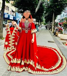 a woman in a red and gold dress on the street