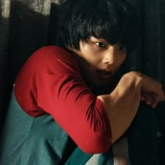 a young man leaning against a wall with his hand on the back of his shoulder