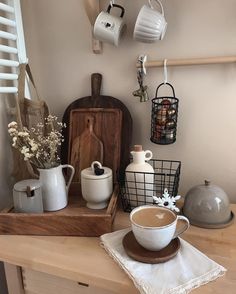 a wooden table topped with cups and saucers next to a shelf filled with utensils