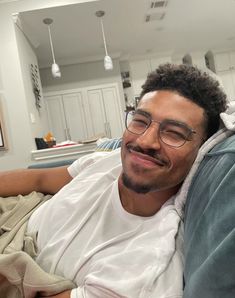 a man laying on top of a couch wearing glasses