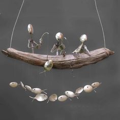 an insect mobile is suspended on a branch with tiny fish and other small objects attached to it