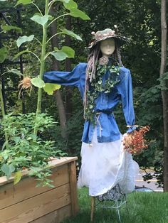 a mannequin dressed in blue and white stands next to a garden with sunflowers