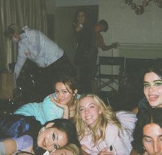 a group of young women laying on top of a bed next to each other in a living room