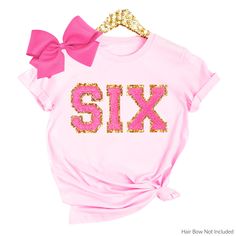 a pink shirt with the word six printed on it and a bow at the front