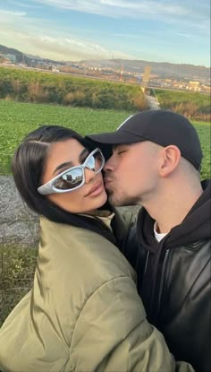 a man and woman kissing while wearing sunglasses