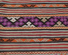 an orange, purple and black striped rug with different designs on the edges is shown