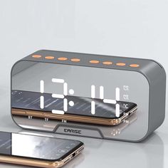 an alarm clock with two phones next to it