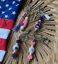 the american flag is next to two keychains with beads and tassels on them