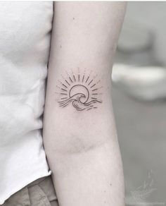 a woman's arm with a sun and wave tattoo on the left inner arm