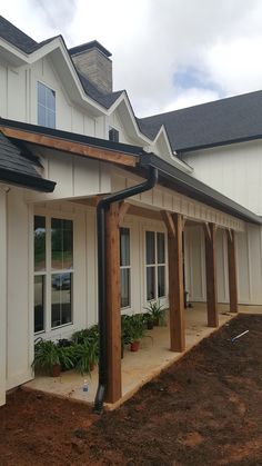 an outside view of a white house with wood trimmings and plants on the side