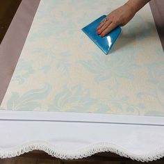 a person with a blue cloth on top of a white bed sheet and cleaning it