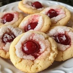 cookies with powdered sugar and cherries are on a white plate, ready to be eaten