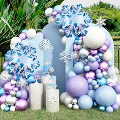 an outdoor display with balloons, snowflakes and other decorations on the grass in front of a gate