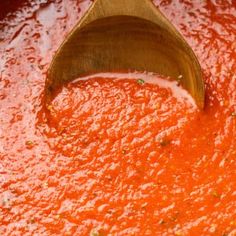 a wooden spoon is in a red sauce