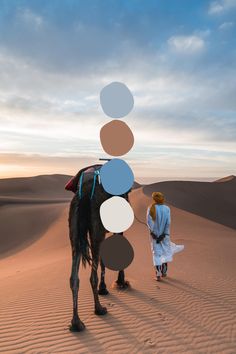 a man and woman are walking in the desert with a camel that has circles on it