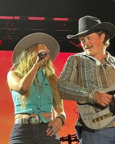 two people with hats on and one holding a guitar while the other holds a microphone