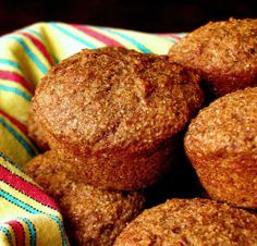 some muffins are sitting in a bowl on a tablecloth with a striped napkin