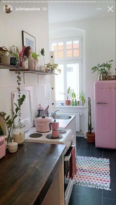 a kitchen with pink appliances and plants on the counter