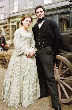 a man and woman standing next to each other in front of a horse drawn carriage