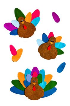 three turkeys made out of felt sitting on top of a white surface with colorful feathers