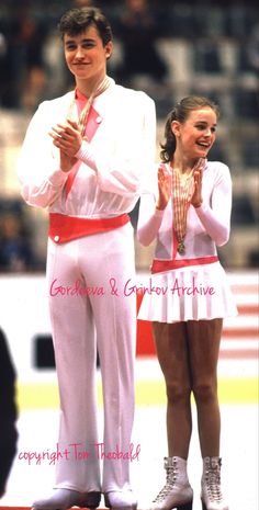 two people standing next to each other with their hands in the air while wearing white and red outfits