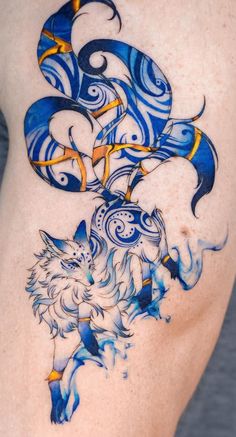 an artistic tattoo on the back of a woman's thigh, with blue and yellow designs