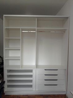 an empty closet with white shelves and drawers