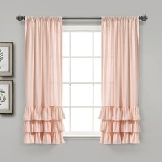 a window with pink curtains and pictures on the wall