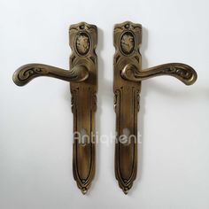 two antique style door handles with clock faces on each handle and one has a keyhole in the middle