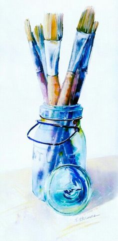 a jar filled with paint brushes sitting on top of a table