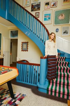 a woman standing in front of a blue stair case next to a table with a game on it