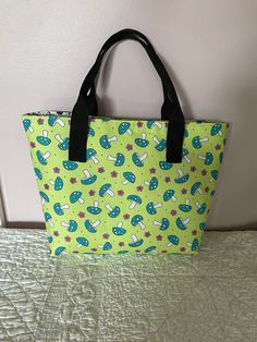 "This mushroom tote is just adorable.  The exterior fabric is covered in large mushrooms and pink flowers on a light lime background.  The interior is covered with mushrooms in black and white!  The bag measures 10.25\" wide by 9.25\" tall by 4 1/4\" deep.  It measures 13.25\" across the top.  The bag from the bottom to the top of the handles measures 14.25\".  It has a magnetic closure at the top of the bag. It has two interior pockets that measure 6 1/2\" wide by 5 1/2\" tall.  The divider pocket measures 11 \" wide by  6\" tall and is made in the lime green mushroom print fabric and is lined with the black and white mushroom fabric. It has a 8.75\" zipper. The handles have about a  5\" drop. The interior of this bag is interfaced with fusible fleece and a medium weight stabilizer which Spring Green Canvas Shoulder Bag, Green Canvas Shoulder Bag For Spring, Spring Green Canvas Bag, Green Outdoor Tote Shoulder Bag, Green Tote Shoulder Bag For Outdoor, Green Tote Lunch Bag For Daily Use, Casual Green Lunch Bag For Everyday Use, Green Fabric Bag For Summer, Casual Green Tote Lunch Bag