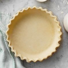 an uncooked pie crust sitting on top of a table next to some eggs