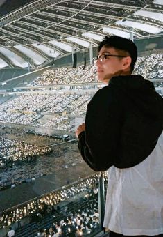 a man standing in front of a stadium filled with lots of white lights and people sitting on the bleachers