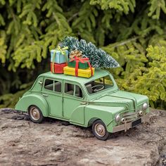 a toy car with presents on top sitting on a rock in front of some trees