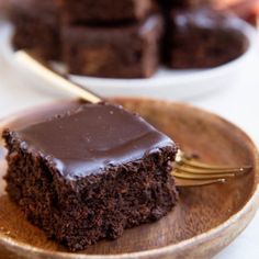 a piece of chocolate cake sitting on top of a wooden plate with a fork in it