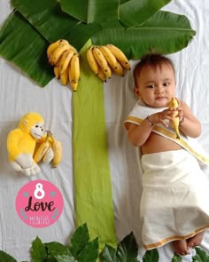 a baby is holding bananas in front of a banana tree and stuffed animals on the floor